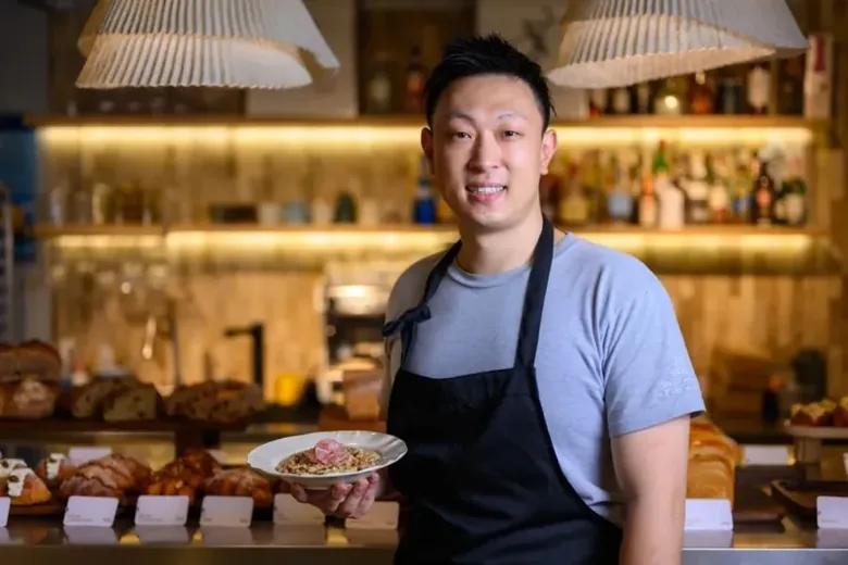 A chef behind a service counter with charcuterie plates.
