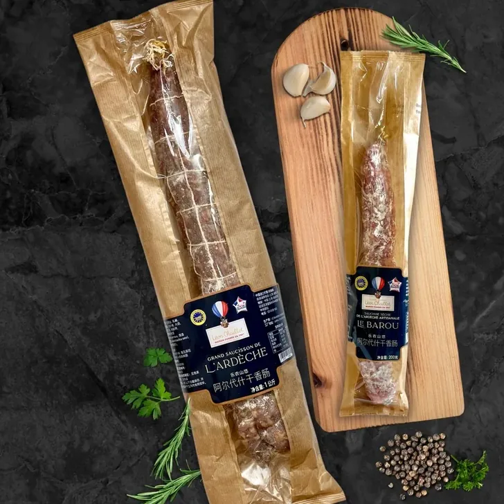 Grand Saucisson de l’Ardèche and Le Barou presented on a board with garlic and peppercorns.
